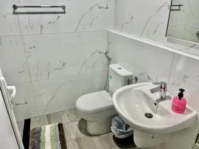 a white bathroom with a toilet and a sink at Karama stunning unit for 4 in Dubai