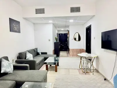a living room with couches and a flat screen tv at Mina Road AL Thayer in Dubai