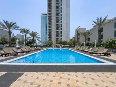 a swimming pool with lounge chairs and a building at Classy Studio in the Heart of Greens in Dubai