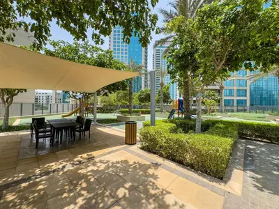 a patio with a table and chairs in a park at Classy Studio in the Heart of Greens in Dubai