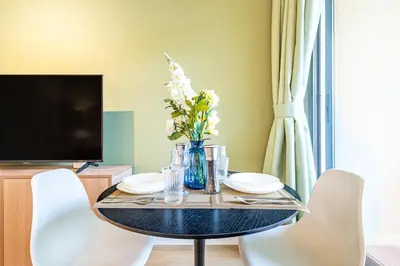 a dining room table with a vase of flowers on it at Classy Studio in the Heart of Greens in Dubai