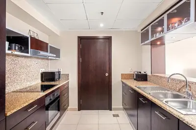 a large kitchen with a sink and a wooden door at Elegant 1-Bedroom Apartment in Dubai Marina in Dubai