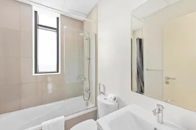 a white bathroom with a sink and a mirror at Elegant 3BR Villa with Access to Pool & Gym in Dubai