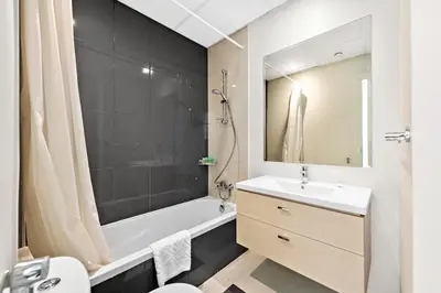 a bathroom with a white tub and a sink and a mirror at Elegant 3BR Villa with Access to Pool & Gym in Dubai