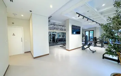 an empty room with a gym with a woman doing exercises at Modern 1BR Steps from Burj AlArab Madinat Jumeirah By AYA Boutique in Dubai