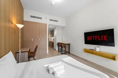 a bedroom with a bed and a television on a wall at Charming Studio with Pool, Gym, Kid's playground in Dubai