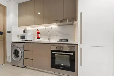 a kitchen with a stove and a washing machine at Charming Studio with Pool, Gym, Kid's playground in Dubai