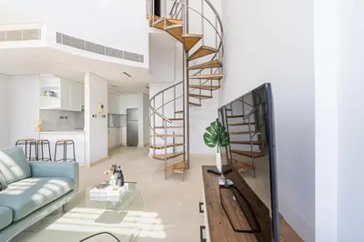 a living room with a blue couch and a spiral staircase at Chic Urban Loft SkyGardens DIFC, Dubai in Dubai