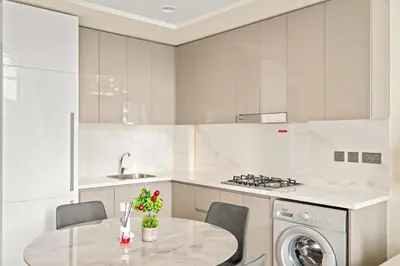 a white kitchen with a table and a dishwasher at VayK - Modern 1BR with Spacious Terrace in Dubai