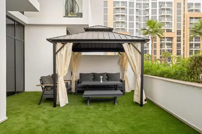 a gazebo on a balcony with green grass at VayK - Modern 1BR with Spacious Terrace in Dubai