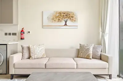 a living room with a couch and a tree on the wall at VayK - Modern 1BR with Spacious Terrace in Dubai