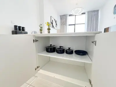 a kitchen with white shelves with pots and pans at Modern Studio with Stunning City Views in Dubai