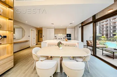 a dining room with a table and chairs and a kitchen at Kensington Waters, MBR City, Dubai in Dubai