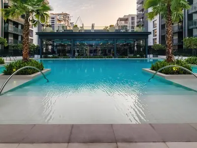 a swimming pool in the middle of a building with palm trees at Kensington Waters, MBR City, Dubai in Dubai