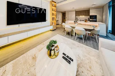 a living room with a large tv and a table at Kensington Waters, MBR City, Dubai in Dubai