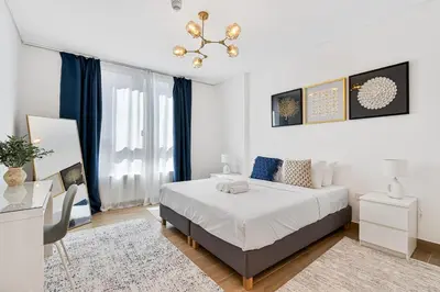 a bedroom with a bed and a chandelier at Stylish 1BR Port De La Mer Escape with Beach Access in Dubai