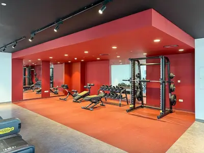 a gym with several tread machines in a red wall at Stylish 1BR Port De La Mer Escape with Beach Access in Dubai