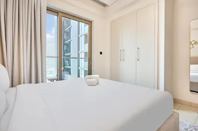a white bedroom with a large bed and a window at STAY BY LATINEM Luxury 1BR Holiday Home CVR A1814 near Burj Khalifa in Dubai
