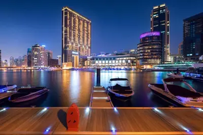 a boat in the water with a city at night at Amazing Dubai Marina Studio Pool Beach Sea View in Dubai
