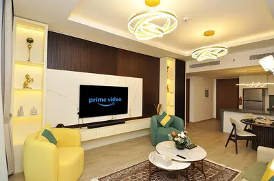 a living room with a tv and a yellow chair at Luxury 1 Bedroom Burj Khalifa View Citywalk in Dubai