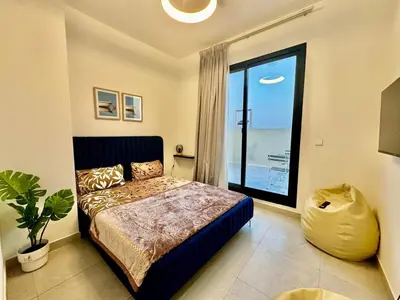 a bedroom with a bed and a large window at Spacious unit with a terrace in Dubai