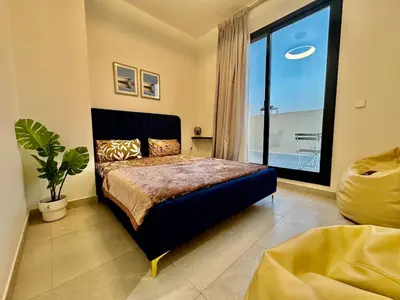 a bedroom with a bed and a large window at Spacious unit with a terrace in Dubai