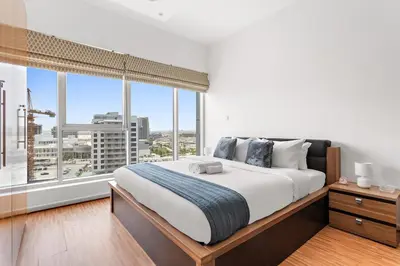 a bedroom with a large bed and a large window at Modern Studio in Skycourts, Near Dubai Outlet Mall in Dubai