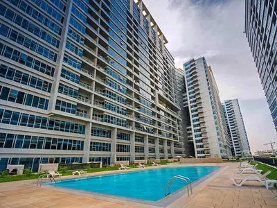a large building with a swimming pool and two tall buildings at Modern Studio in Skycourts, Near Dubai Outlet Mall in Dubai