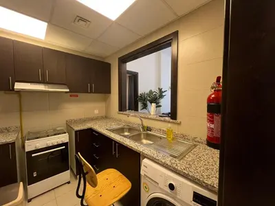 a kitchen with a sink and a stove and a window at Jaddaf Pool Gym Parking in Dubai