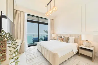 a white bedroom with a bed and a large window at Luxury 2BR in Beach Vista With Stunning Palm Views in Dubai