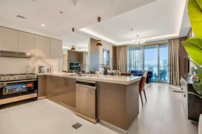 a kitchen with stainless steel appliances and a living room at Burj Khalifa view, 3 Bedroom, Maids Room, Forte in Dubai