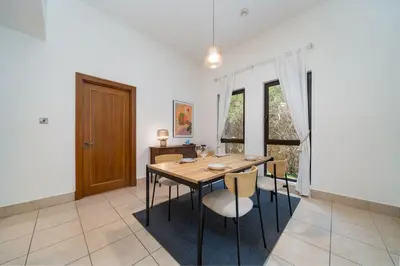 a dining room with a wooden table and chairs at Stylish Old Town 1 Bed Plus Maids with Private Garden in Dubai