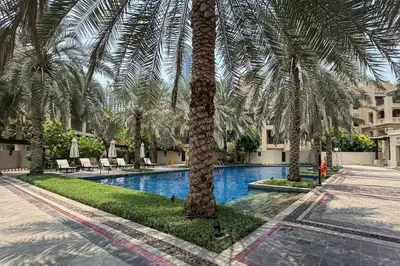 a palm tree in front of a swimming pool at Stylish Old Town 1 Bed Plus Maids with Private Garden in Dubai