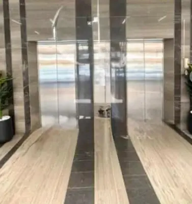 a lobby with glass walls and a wooden floor at SAM Homes in Dubai