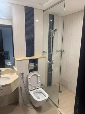 a bathroom with a toilet and a glass shower at SAM Homes in Dubai