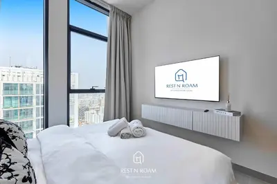 a bedroom with a bed with a tv on the wall at Brand New 1BR Near Parks and Mall JVC in Dubai