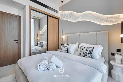 a bedroom with a large white bed with towels on it at Brand New 1BR Near Parks and Mall JVC in Dubai