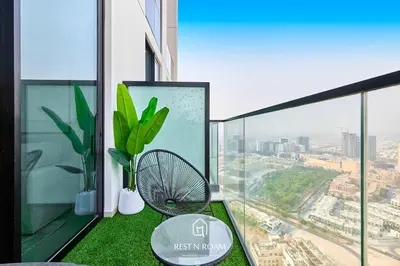 a balcony with green grass and a table and a window at Binghatti Gardenia 1BR - Near Parks and Mall JVC in Dubai