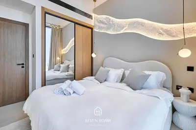 a bedroom with a large white bed and a mirror at High Floor 1BR - Near Parks and Mall - JVC in Dubai