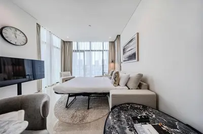 a living room with a couch and a clock on the wall at Peninsula Five 3BD Duplex with Lake view, For 9 in Dubai