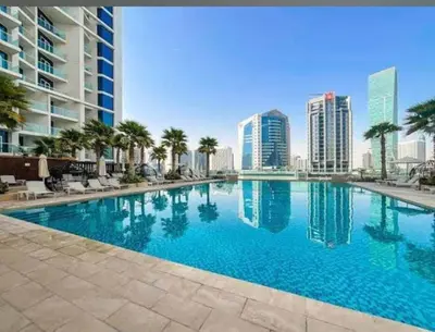 a large swimming pool with palm trees and buildings at Charming Studio and Perfect Stay with Gym and Pool in Dubai