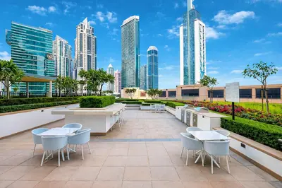 a patio with tables and chairs in front of a city skyline at Exceptional 2 Bedroom Apartment! High Floor! Amazing Rooftop! Burj Crown by Emaar in Dubai