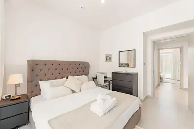 a white bedroom with a large bed and a desk at Spacious 4BR Villa with Private Garden & Patio in Nadd Shubayḩ