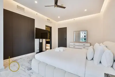 a white bedroom with a large white bed and a flat screen tv at Bookable - Penthouse 5,000sqft by Downtown Dubai in Dubai