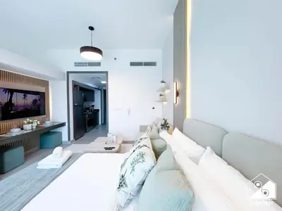 a bedroom with a large white bed with pillows at Urban Escape Studio l Pool, Gym & Stylish Living in Dubai