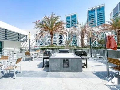 a patio with tables and chairs and palm trees at Urban Escape Studio l Pool, Gym & Stylish Living in Dubai