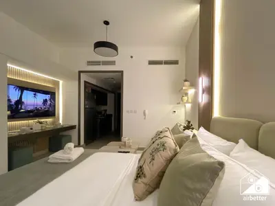 a bedroom with a white bed and a television at Urban Escape Studio l Pool, Gym & Stylish Living in Dubai