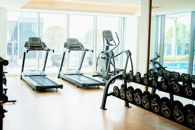 a gym with several tread machines in a room at Urban 1BR Stay, Walk to Downtown & Canal in Dubai