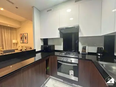 a kitchen with white cabinets and a stove top oven at Urban 1BR Stay, Walk to Downtown & Canal in Dubai