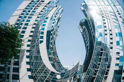 a tall glass building with the sun shining on it at Urban 1BR Stay, Walk to Downtown & Canal in Dubai